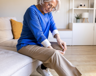 Woman grimacing in pain and holding her knee