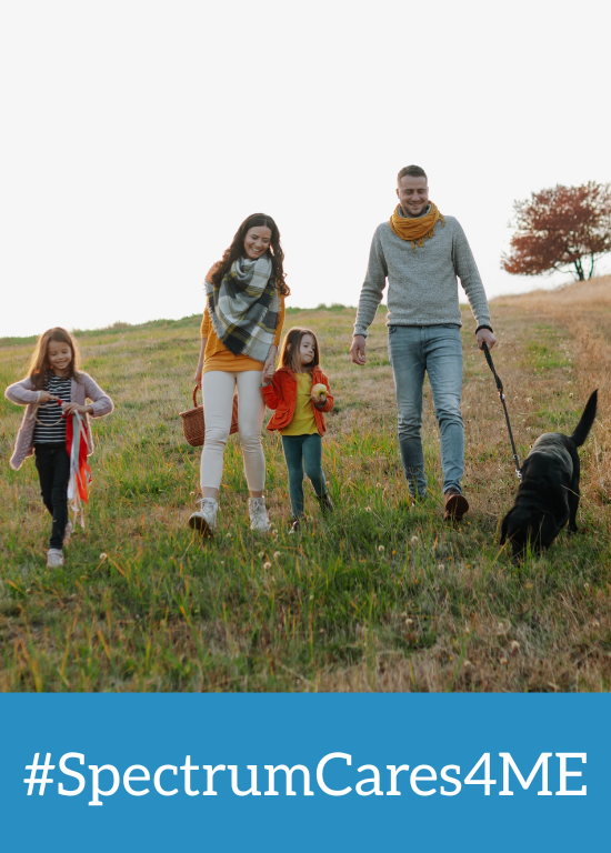 Family walking through a field with their dog in springtime