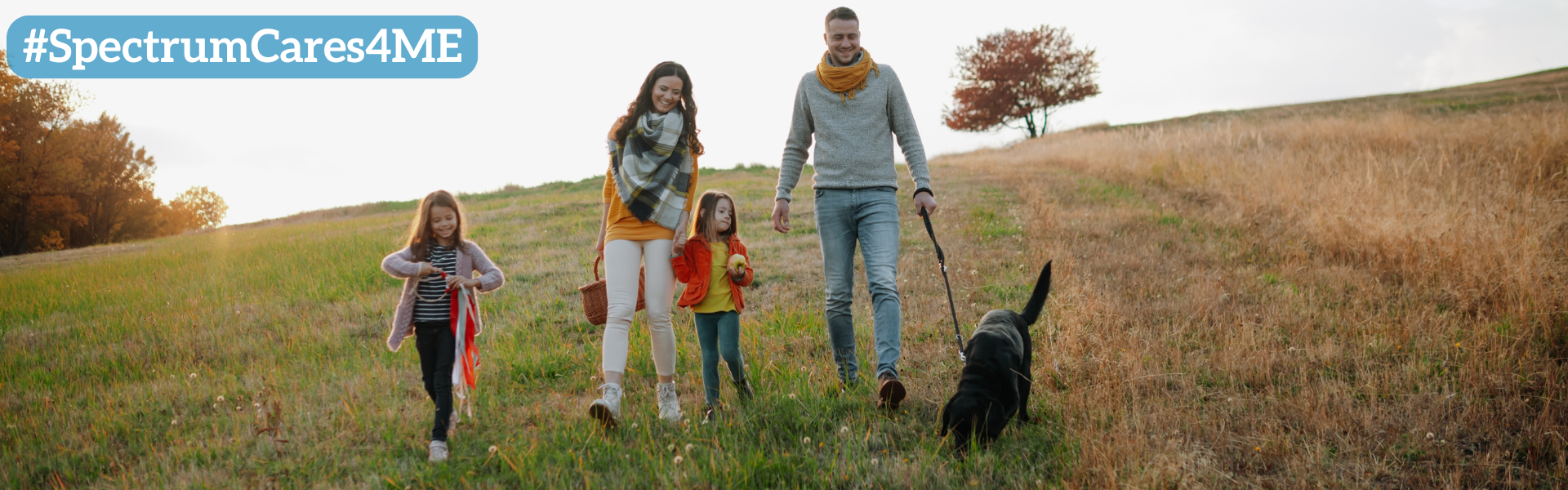 Family walking through a field with their dog in springtime
